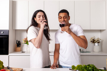 young happy multiracial couple drink wine in white modern kitchen, african american guy clink glasses with girl