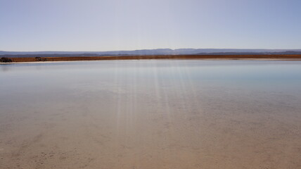 Foto de um lago no meio do deserto do Atacama, no Chile, destacando a beleza única da paisagem desértica com a água cristalina contrastando com o árido cenário ao redor © RNL Fotografia