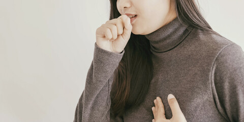 Close up of young Asian woman coughing from cold and flu,COPD, pneumonia, bronchitis, asthma,...