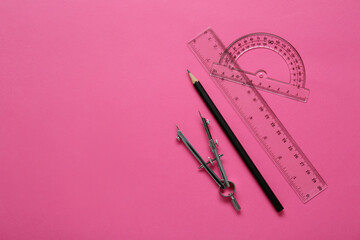 Ruler, protractor, pencil and compass on pink background, flat lay. Space for text - obrazy, fototapety, plakaty