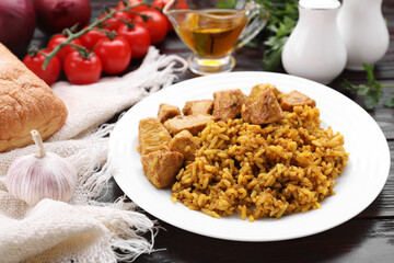 Delicious rice with chicken served on wooden table, closeup