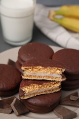 Tasty banana choco pies and pieces of chocolate on plate, closeup. Space for text