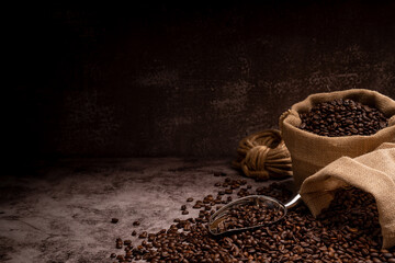 The picture of coffee beans stacked together on a wooden floor in a warm, light atmosphere, on a dark background, with copy space.