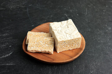 Raw Tempeh or Tempe. Tempeh Slices on Wooden Plate