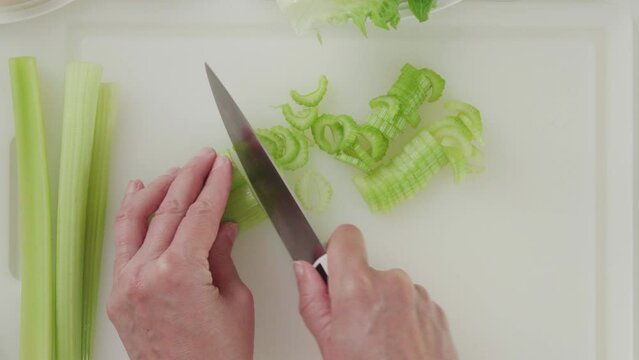 Fresh green celery chopped on cutting board. Celery lettuce salad recipe, ingredients close-up on white background