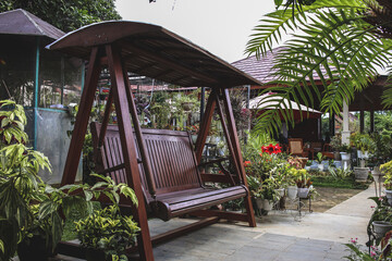 Cozy house terrace with wooden garden swing and assortment plants