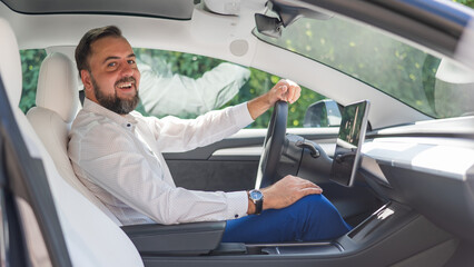Caucasian bearded man in a suit driving a car. 