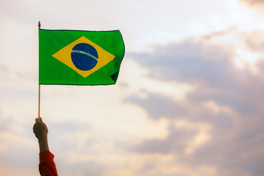 Hand Waving the Flag of Brazil on the Sky. Brazilian holding national flag celebrating  7 of September 
