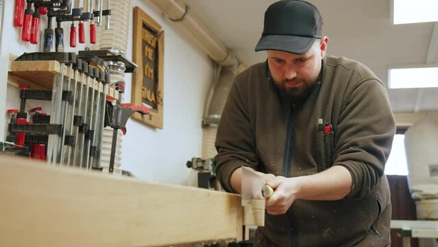 Caucasian carpenter using a tenon saw and cutting wood in his workshop, medium shot. High quality 4k footage
