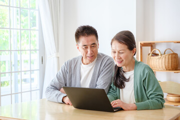 Obraz premium リビングでパソコンを使うシニア夫婦