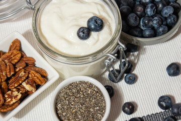 Glass jar with natural organic homemade yogurt and blueberries pecan nut chia seeds pudding. Immunity-boosting ingredients. Concept of healthy eating breakfast of Greek yogurt in glass jar and fresh