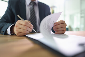 Male employee flips page of contract signing after reading