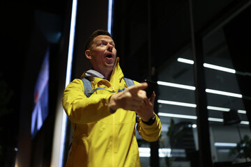 Male tourist with backpack got lost in city uses navigation