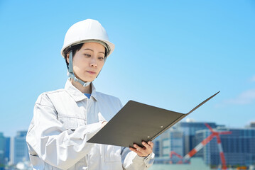 現場を確認する作業着姿の女性