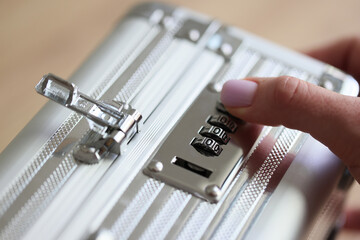 Hand of woman setting up password to unlock silver briefcase