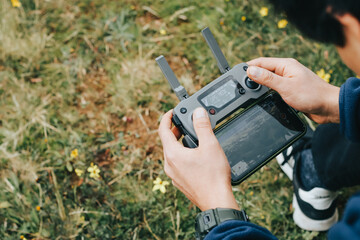 Photograph of a man's hands holding the remote control of a Drone (Drone Operator). Technology concept