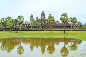 Fototapeta na wymiar Scenery of Angkor Wat across the lake and the reflection in the water during thw cloudy sunrise. UNESCO world heritage site in Cambodia