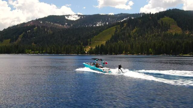 Aerial cinematic drone Lake Tahoe man wake surf boat wave stunning  polarized aqua blue spring summer beautiful daytime 8 California Nevada north shore Homewood follow movement to the left Tahoe Surf