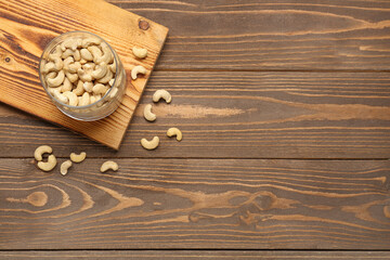 Fototapeta na wymiar Jar with tasty cashew nuts on wooden background