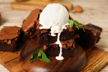 Board with pieces of tasty chocolate brownie and ice cream on table