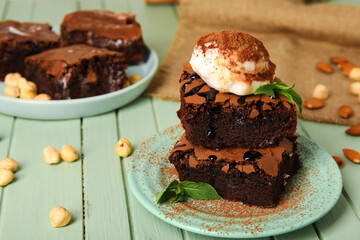 Plate with pieces of tasty chocolate brownie and ice cream on green wooden background