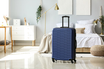 Blue suitcase in light bedroom