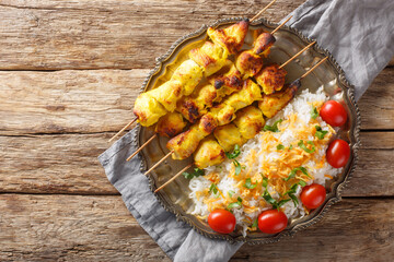Joojeh Kabab is a deliciously tender Persian chicken kabob that has a unique saffron flavour served with rice closeup on the plate on the table. Horizontal top view from above - obrazy, fototapety, plakaty