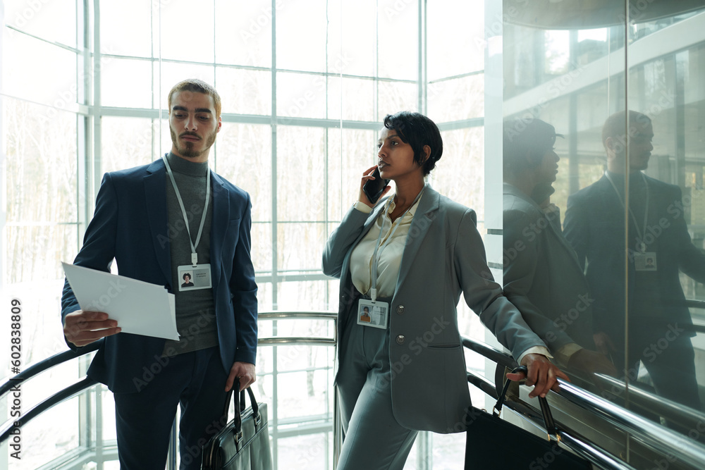 Poster young male delegate looking through report points while standing next to female colleague in formalw