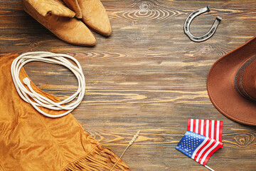 Composition with different cowboy accessories and flag of USA on brown wooden background
