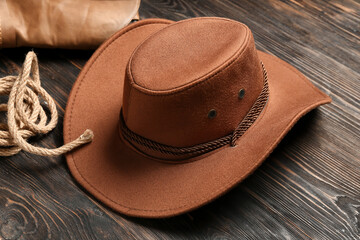 Cowboy hat, boots and lasso on brown wooden background
