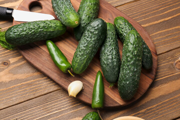 Board with fresh cucumbers for preservation on wooden background