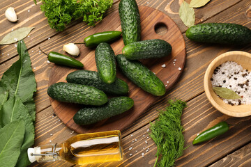 Board with fresh cucumbers and ingredients for preservation on wooden background