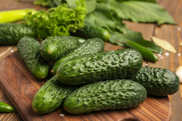 Wooden board with fresh cucumbers for preservation on table, closeup
