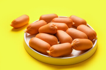 Plate of tasty boiled sausages on yellow background