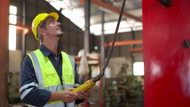 Factory worker - technician controlling a heavy crane in factory close up at his hands holing a crane controller.