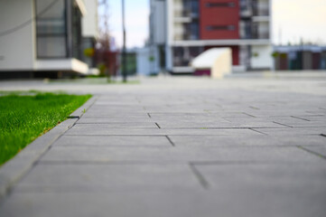 A green lawn stretches out before tall, modern urban houses, offering a serene contrast to the bustling cityscape.