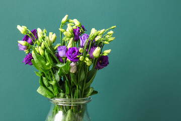 Glass vase with eustoma flowers on blue background