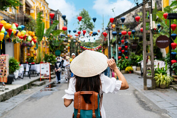 Carefree Asian tourist woman wearing Non La (traditional Vietnamese hat) enjoy sightseeing in Hoi...