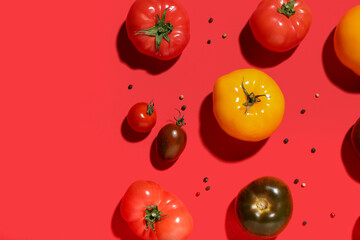 Different fresh tomatoes and peppercorn on red background