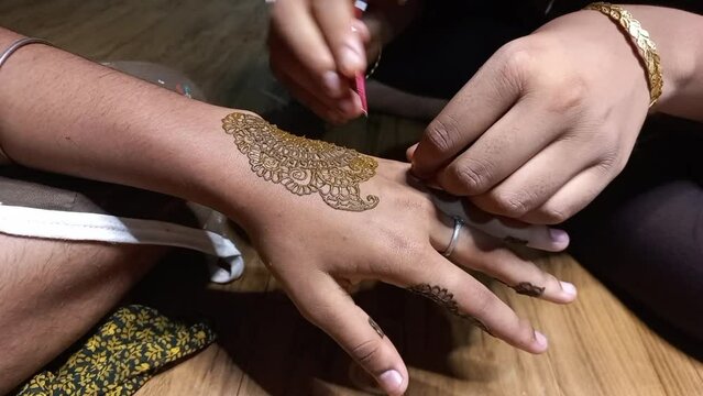 Young Teen Age Indian Girl painting henna Tattoo on the hand