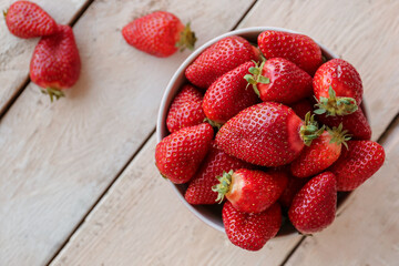 Bowl with fresh strawberries on white wooden table