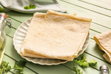 Plate with fresh lavash on green wooden background