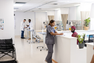 Asian female doctor writing on clipboard at reception desk of hospital ward, copy space