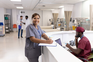 Obraz premium Portrait of happy asian female doctor with clipboard at reception desk of hospital ward