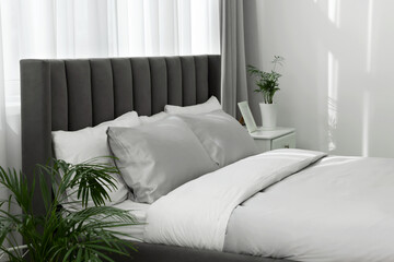 Stylish bedroom interior with comfortable bed and beautiful houseplants