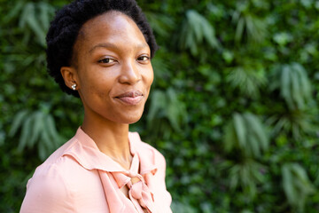 Closeup portrait of smiling african american female architect with short hair posing against plants