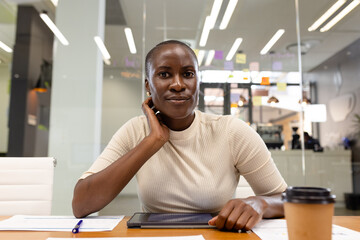 Portrait of african american businesswoman with digital tablet and coffee on desk sitting in office