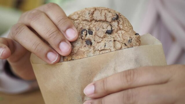 women taking cookies out from a paper packet 