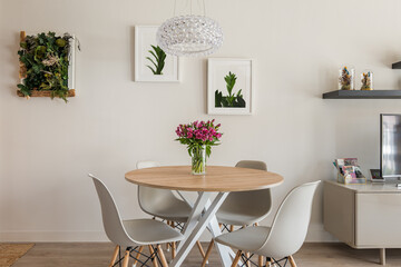 Cozy stylish living room with a round dining table, chairs and TV with decorative accessories on...