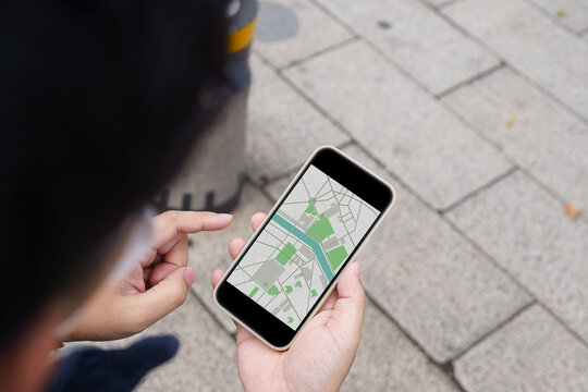 Woman with baggage&nbsp;in downtown city street searching location in map application online on smart phone using GPS&nbsp;navigating.